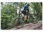 Un homme roule à vélo de montagne gris avec des pneus Maxxis dans une forêt.