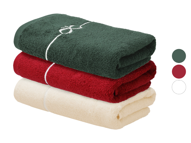 Serviettes LIVARNO® Frottier: vert foncé, rouge et crème, nouées avec un ruban blanc.