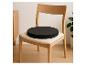 Chaise en bois clair avec coussin de siège rond noir dans un intérieur minimaliste.