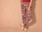 Pantalon femme avec un motif coloré et des sandales blanches.