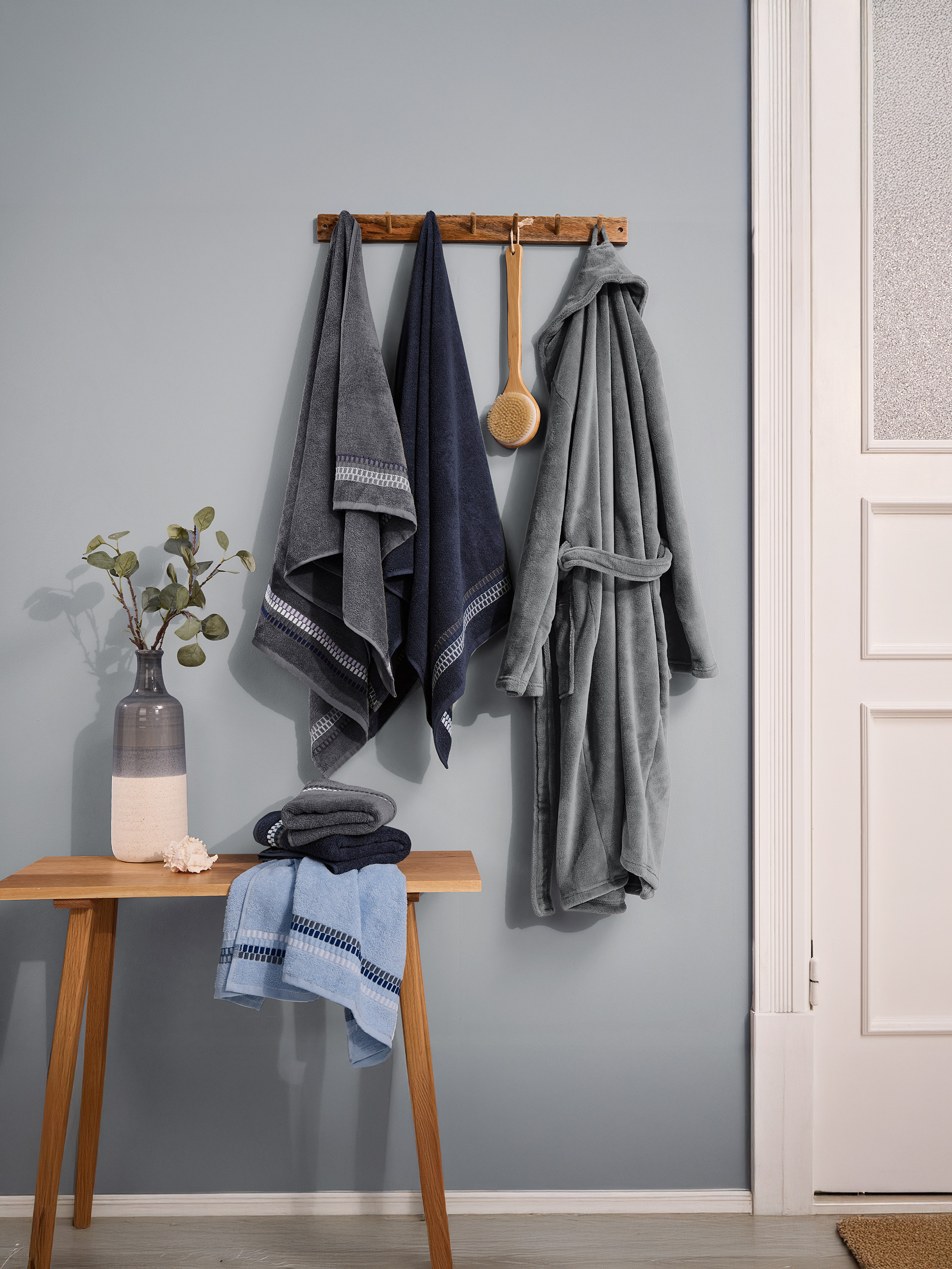 Serviettes et peignoir de bain dans des tons bleus et gris, accrochés au mur.