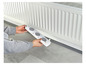 Une personne tient une grille de radiateur avec trois ouvertures de ventilation.