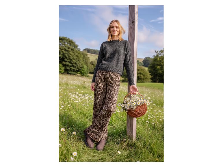 Femme en pull gris et pantalon imprimé léopard, tenant un panier de marguerites.