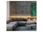 Canapé d'angle gris avec table basse dans un salon moderne aux murs en bois et béton.
