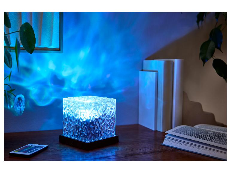 Une lampe LED bleue à surface texturée illumine une pièce, projetant des motifs ondulés sur le mur.