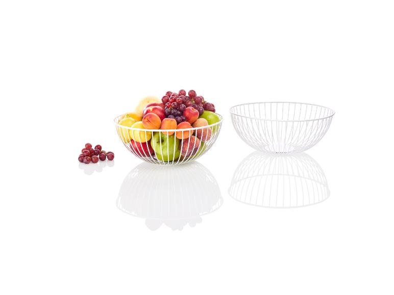 Un bol en métal blanc avec des raisins, des pêches, des pommes et des abricots.