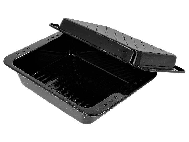 Plat de cuisson noir avec grille d'égouttage, incliné sur fond blanc.