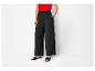 Pantalon large noir et sandales plates : look décontracté élégant.