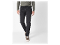 Un homme porte un jean noir et un pull vert olive.