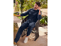 Homme souriant en survêtement bleu marine et baskets blanches, assis à une table de jardin.