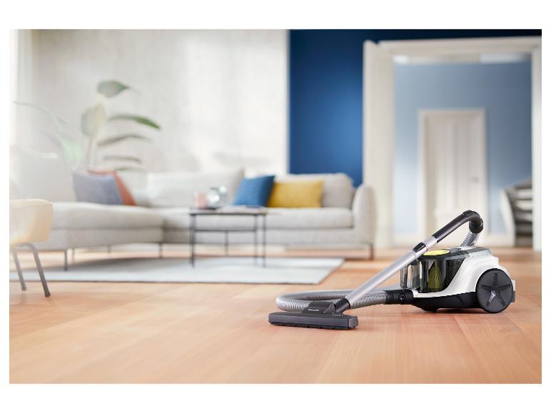 Aspirateur sur parquet dans un salon moderne avec canapé et table basse.