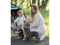 Une femme avec un enfant dans une poussette Ergobaby et un bouledogue français.