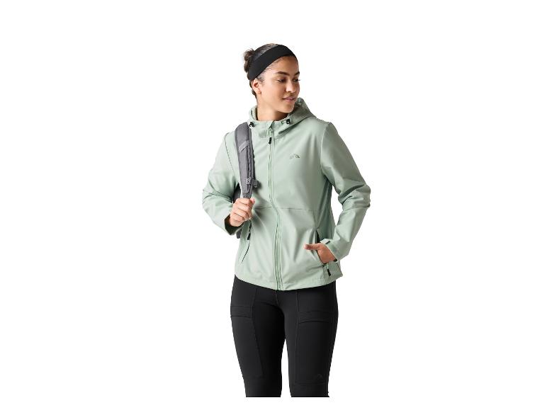 Femme en veste vert clair et legging noir, avec un sac à dos gris.