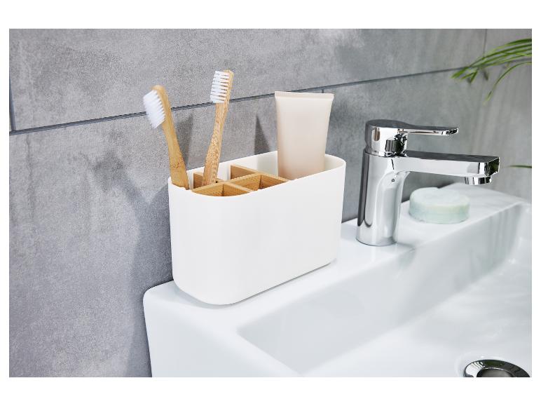 Un organiseur de salle de bain blanc avec deux brosses à dents et un tube de dentifrice.