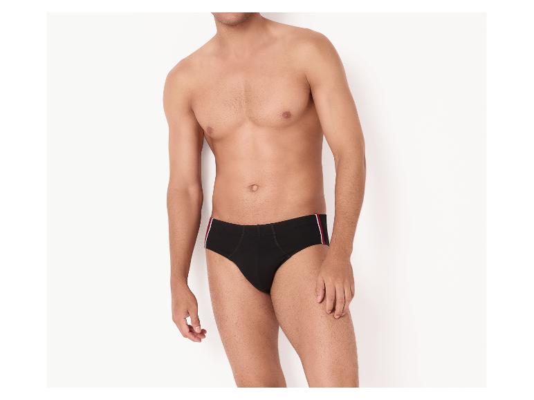 Homme en slip noir avec une bande rouge et blanche sur le côté.