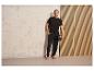 Un homme en pantalon et t-shirt noirs tenant un ballon.
