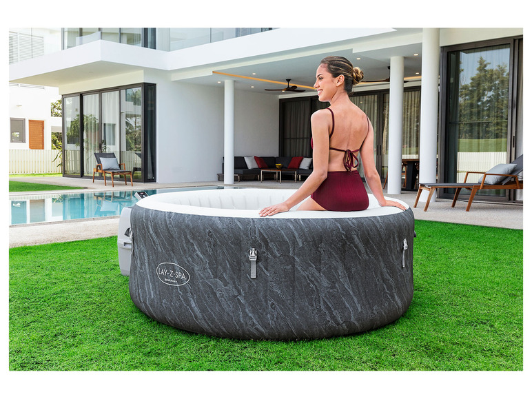 Une femme en maillot de bain se détend dans un jacuzzi gonflable Lay-Z-Spa dans le jardin.