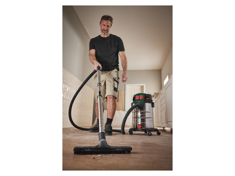 Un homme nettoie le sol avec un aspirateur Parkside.