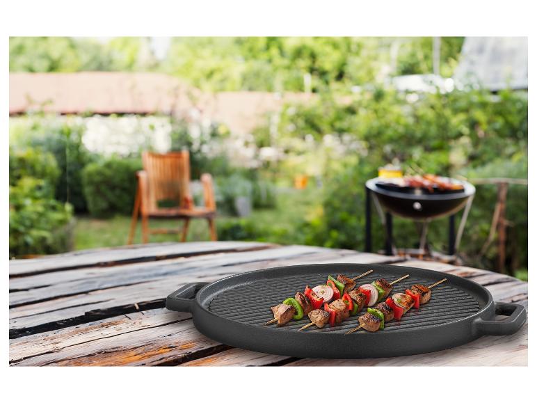 Brochettes de viande et légumes sur une plancha ronde GSW Black Iron BBQ 30cm, dans un jardin.