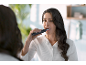 Femme se brossant les dents avec une brosse à dents électrique noire devant un miroir.