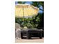 Parasol rayé jaune et blanc, chaise longue et repose-pieds en résine tressée pour l'extérieur.