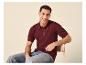 Homme en polo tricoté bordeaux et jean, assis sur une chaise.