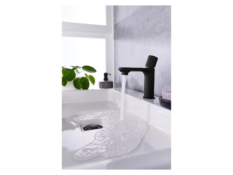 Un robinet moderne noir mat laisse couler l'eau dans un lavabo blanc.