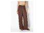 Femme en top clair et pantalon large marron avec des sandales.