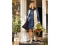 Une femme portant une robe en jean et un gilet beige, tenant un bouquet de fleurs et des bottes beiges.
