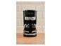 Cafetière noire avec verseuse, affichant « 1973 » sur un fond de carreaux beiges.