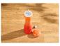 Moulin à poivre orange avec couvercle séparé sur une surface en bois.