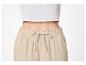 Femme en crop top côtelé blanc et pantalon beige à cordon de serrage.