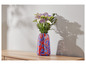 Des fleurs dans un vase en verre rouge et bleu sur une table en bois.