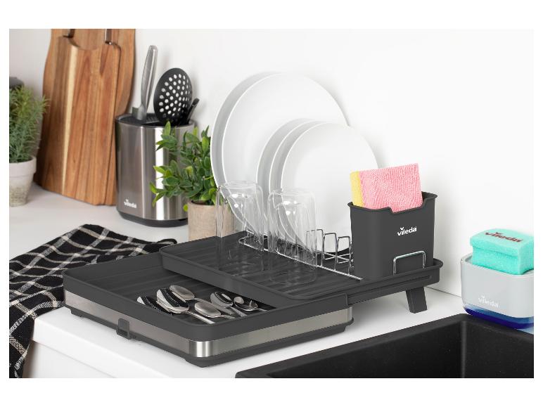 Égouttoir à vaisselle gris avec vaisselle, couverts et accessoires de nettoyage sur un comptoir de cuisine.