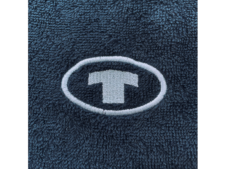 Logo brodé en forme de T dans un ovale sur un tissu éponge bleu foncé.