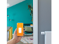 Une main tient un smartphone avec une application de contrôle de thermostats intelligents.