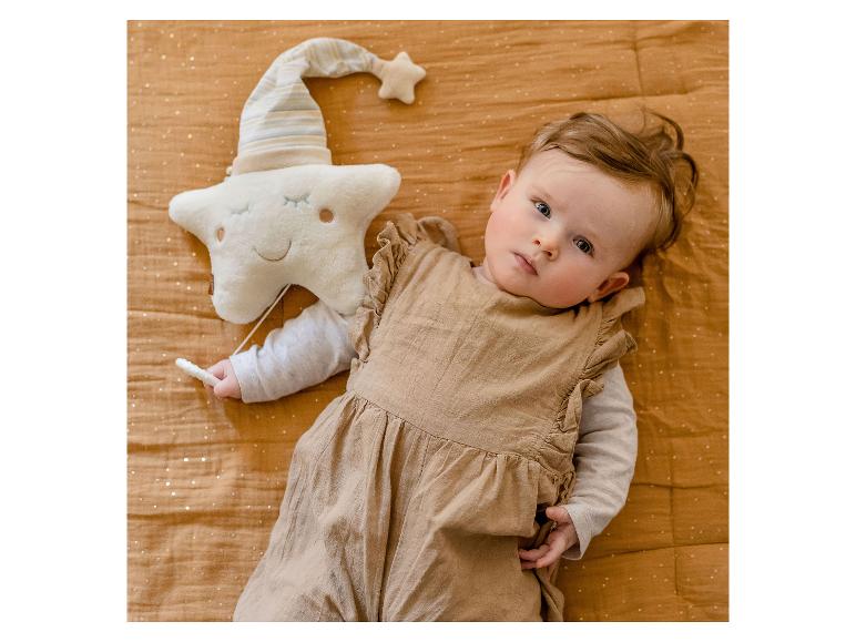 Boîte à musique étoile Fehn à côté d'un bébé allongé sur une couverture