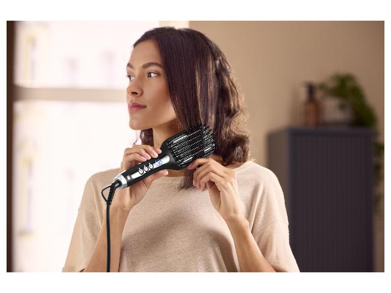 Femme utilisant une brosse lissante électrique pour ses cheveux.