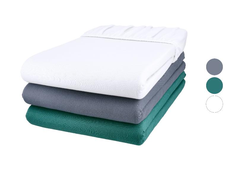 Draps-housses empilés en blanc, gris et vert avec échantillons de couleurs.