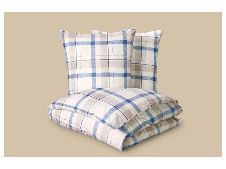 Plaid et deux oreillers à motif écossais bleu et beige.