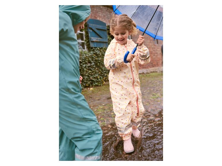 Enfant en imperméable sautant dans une flaque d'eau.