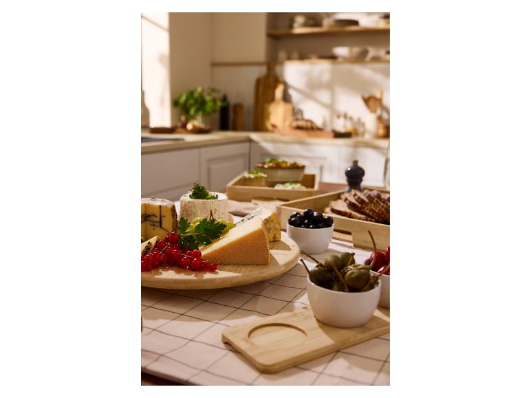 Une sélection de fromages, de baies et d'olives sur une table de cuisine.