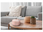 Une bougie rose avec trois mèches sur une table basse en bois.