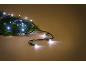 Guirlande lumineuse LED blanche sur une branche de sapin verte, sur fond marron chaud.