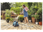 Une femme arrose des plantes en pot avec un tuyau d'arrosage Gardena.