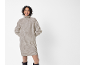 Femme en robe pull col roulé côtelée beige et bottes noires, souriante.