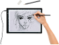 Main dessinant un portrait au crayon sur une table lumineuse à dessin.