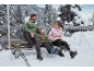 Famille en vestes d'hiver et chaussures de randonnée assise sur un banc dans la neige.