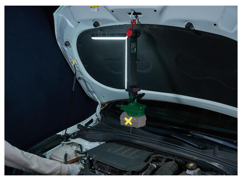 Un mécanicien travaille sur une voiture avec une lampe LED suspendue pour le compartiment moteur.