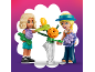 Deux figurines de jeu arrangent des fleurs colorées dans un vase.